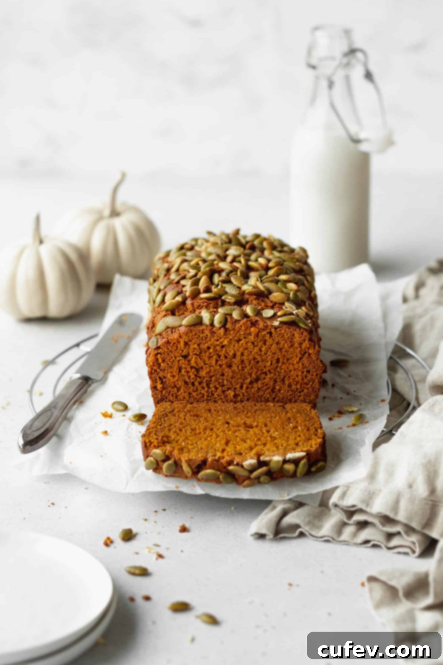 A freshly baked loaf of golden-brown gluten-free pumpkin bread, cooling on a wire rack.