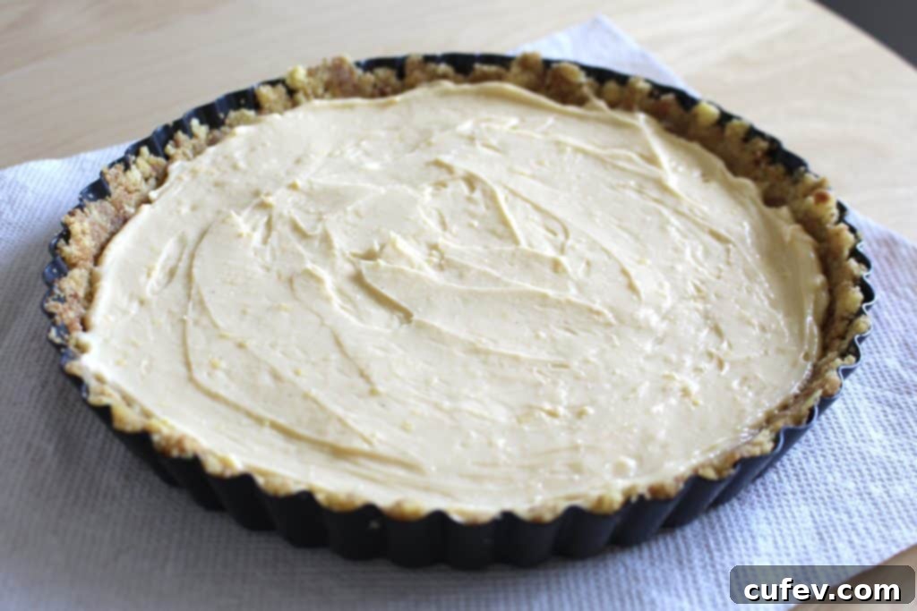 The process of spreading smooth, cooled custard evenly onto the corn cookie crust in a tart pan