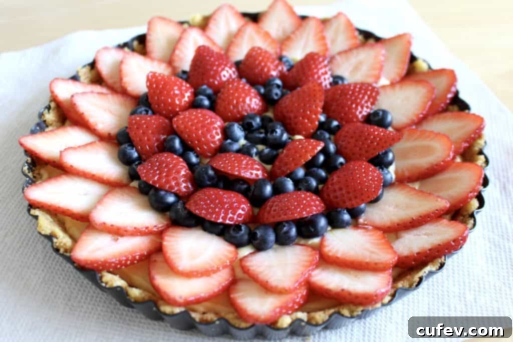 A freshly assembled strawberry and blueberry tart, vibrant with fruit and mint, before its final set