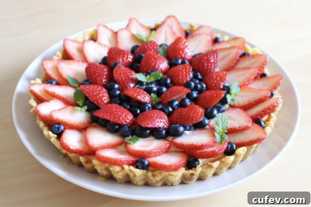 Close-up of a delightful slice of strawberry and blueberry tart, revealing its layered crust, creamy custard, and abundant fresh fruit