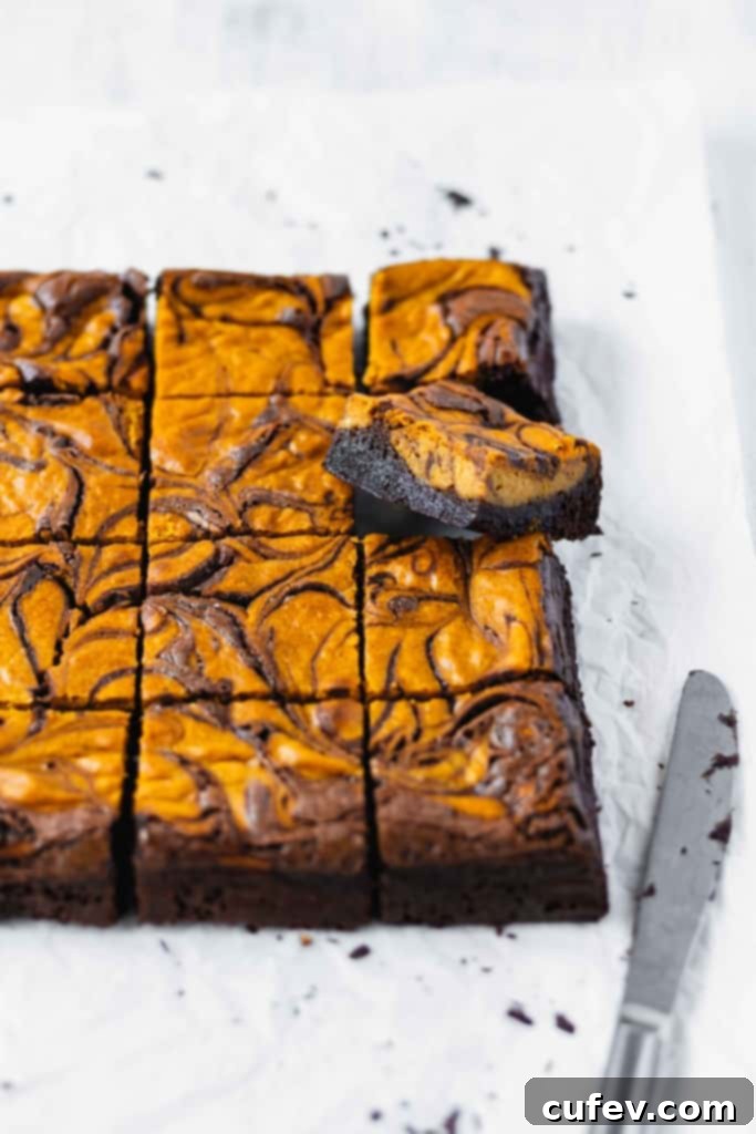A square of pumpkin cheesecake brownie lifted up from the rest of the squares.