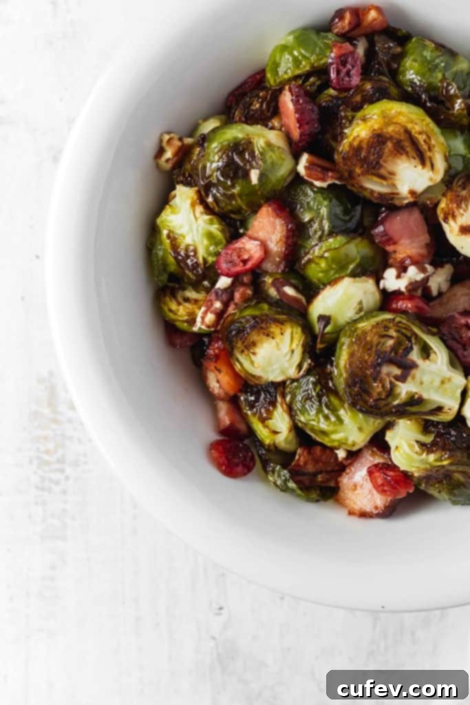 Crispy oven-roasted Brussels sprouts with smoky bacon, sweet dried cranberries, and crunchy pecans – a delicious and easy Thanksgiving side dish.