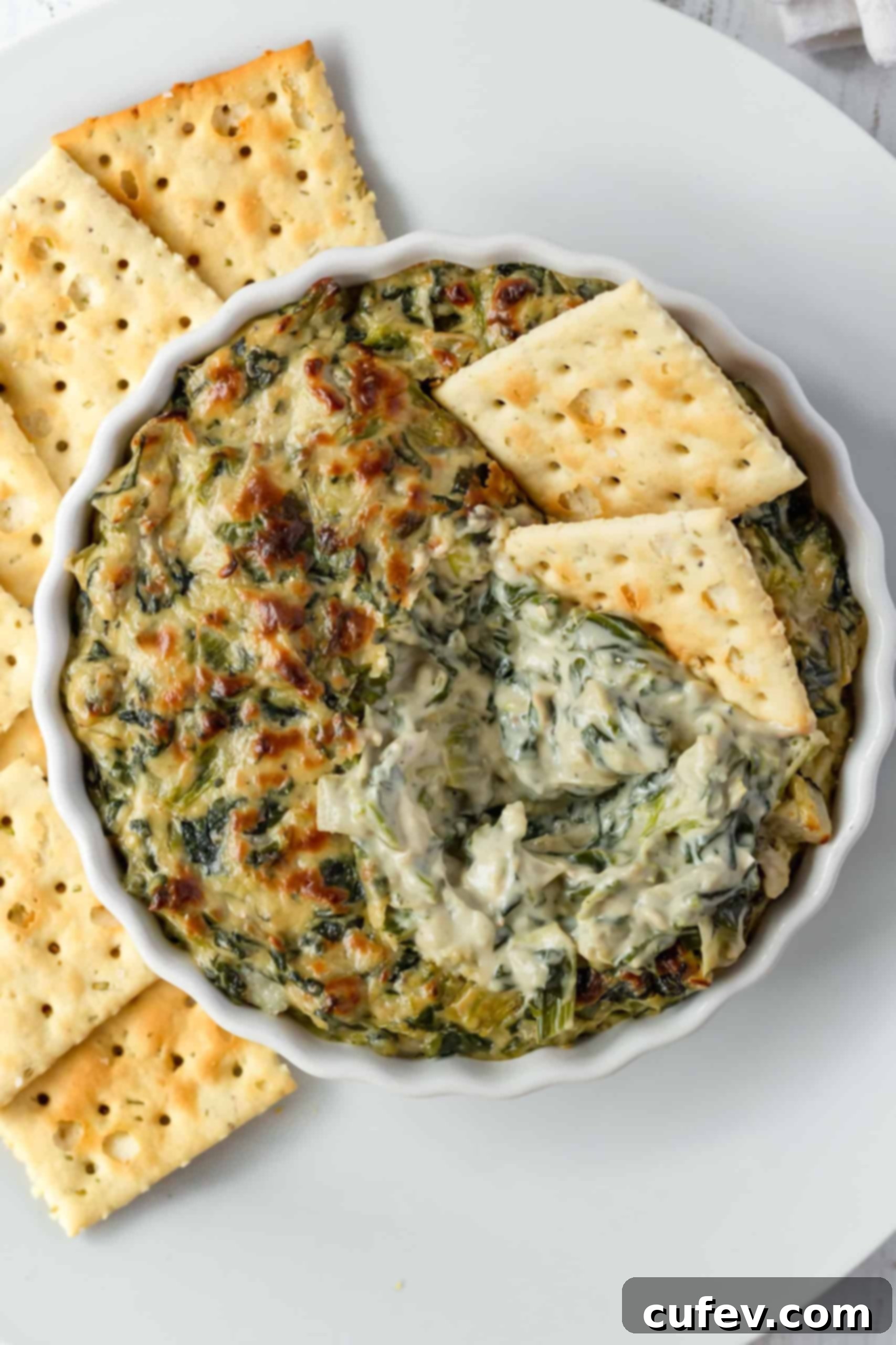 Overhead shot of a vibrant, creamy vegan spinach and artichoke dip, ready to be served.