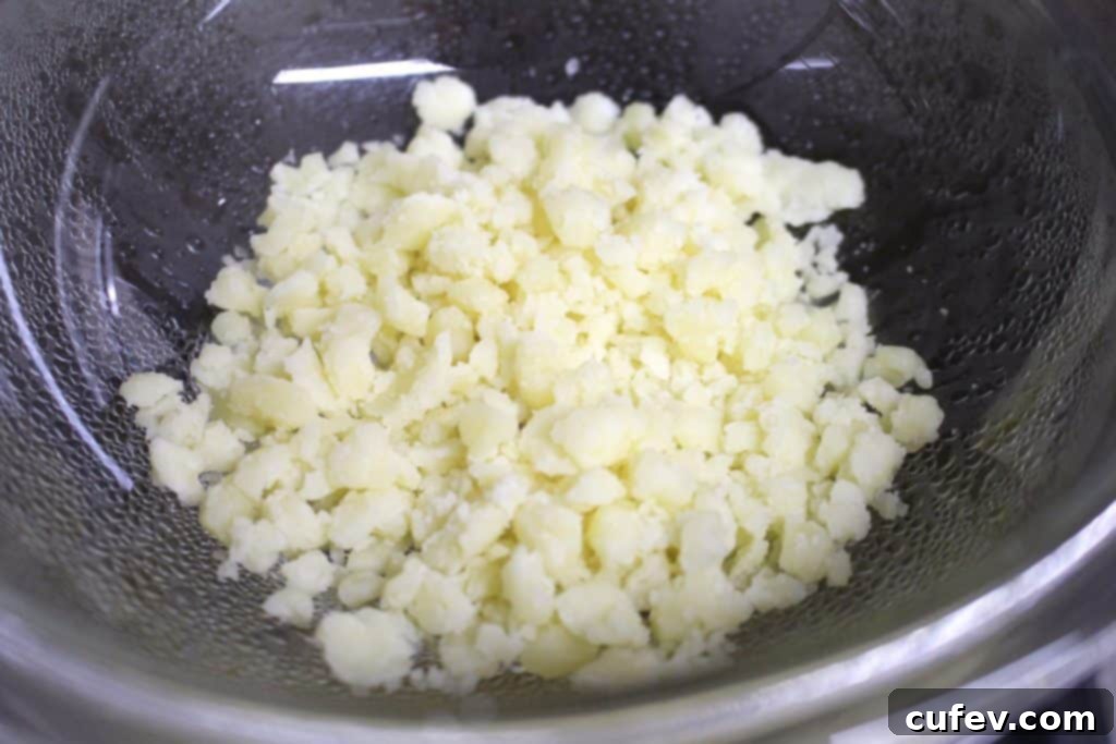 Two Honey Almond Gouda Cheesecakes, one with a spoon, showing the creamy texture and topping