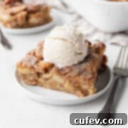Slice of apple pie vegan bread pudding on a white dessert plate, topped with a scoop of vegan ice cream.