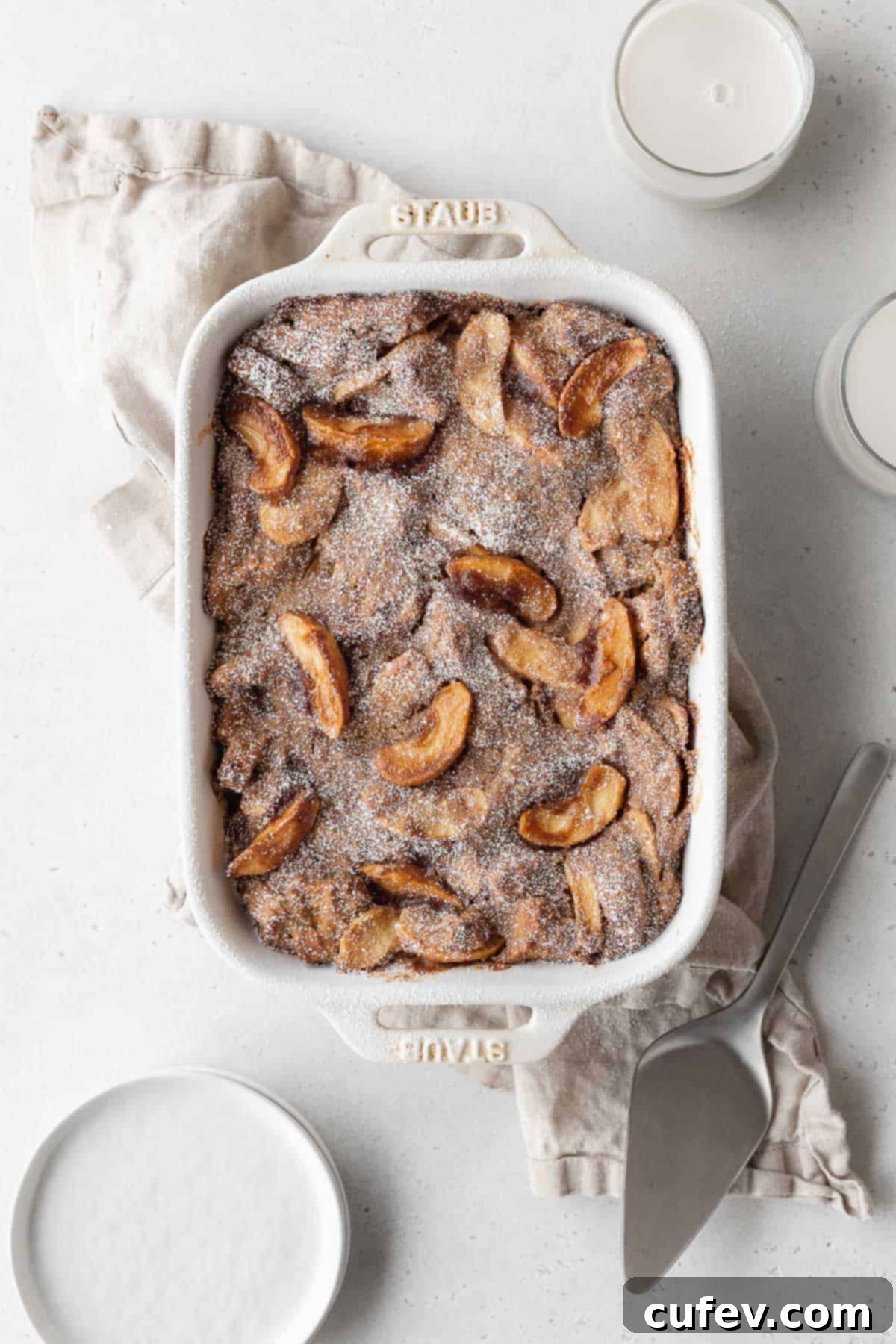 Cozy Vegan Bread Bake 3 An inviting overhead shot of a casserole dish brimming with homemade apple pie-flavored vegan bread pudding, showcasing its golden-brown crust and soft texture.