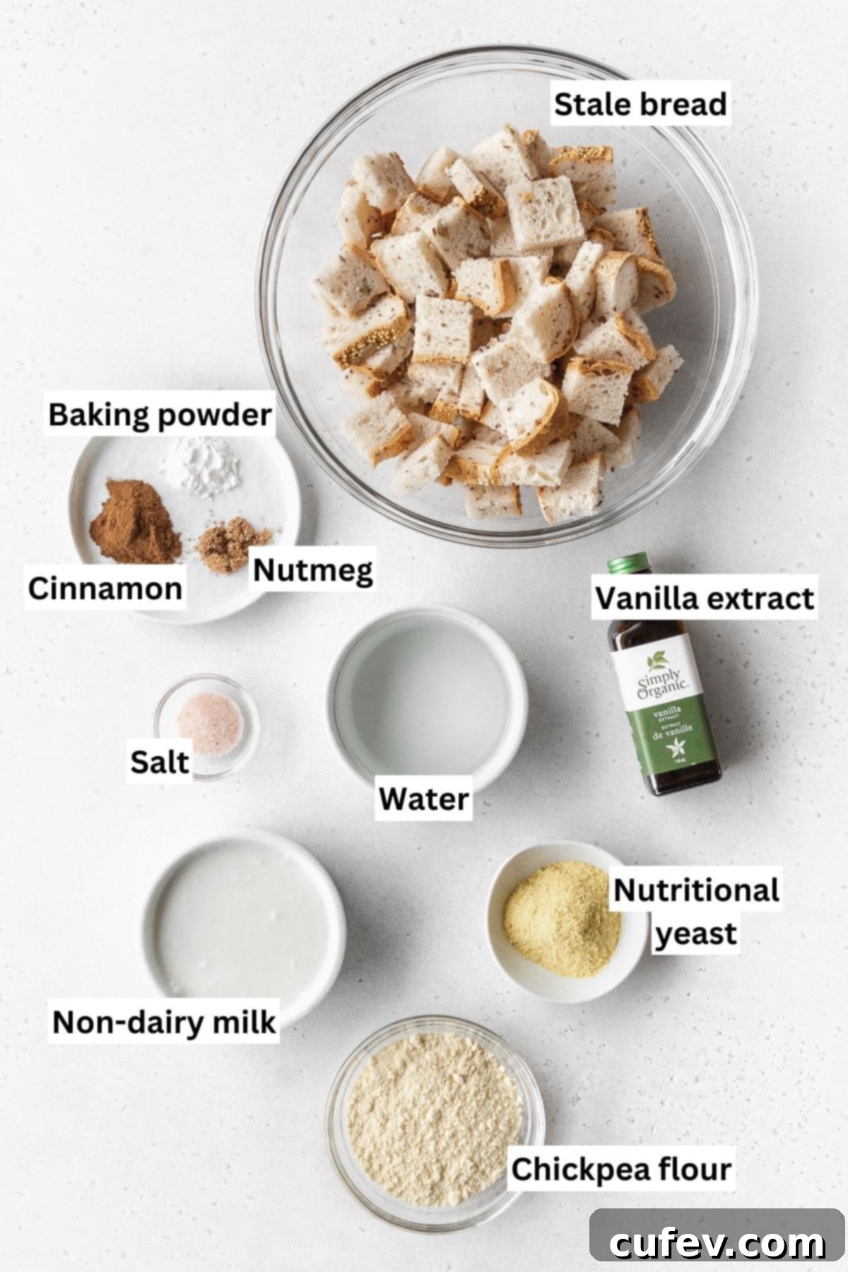 Cozy Vegan Bread Bake 5 An overhead shot showcasing all the essential vegan bread pudding ingredients neatly measured into small bowls, arranged on a clean white surface, ready for preparation.