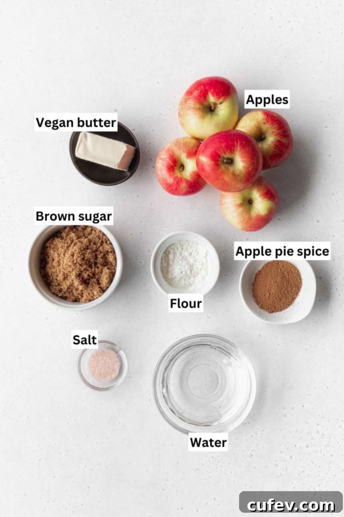 Cozy Vegan Bread Bake 6 An overhead shot showcasing all the pre-measured ingredients for the apple pie filling, neatly arranged in small bowls on a clean white surface, ready to be combined.
