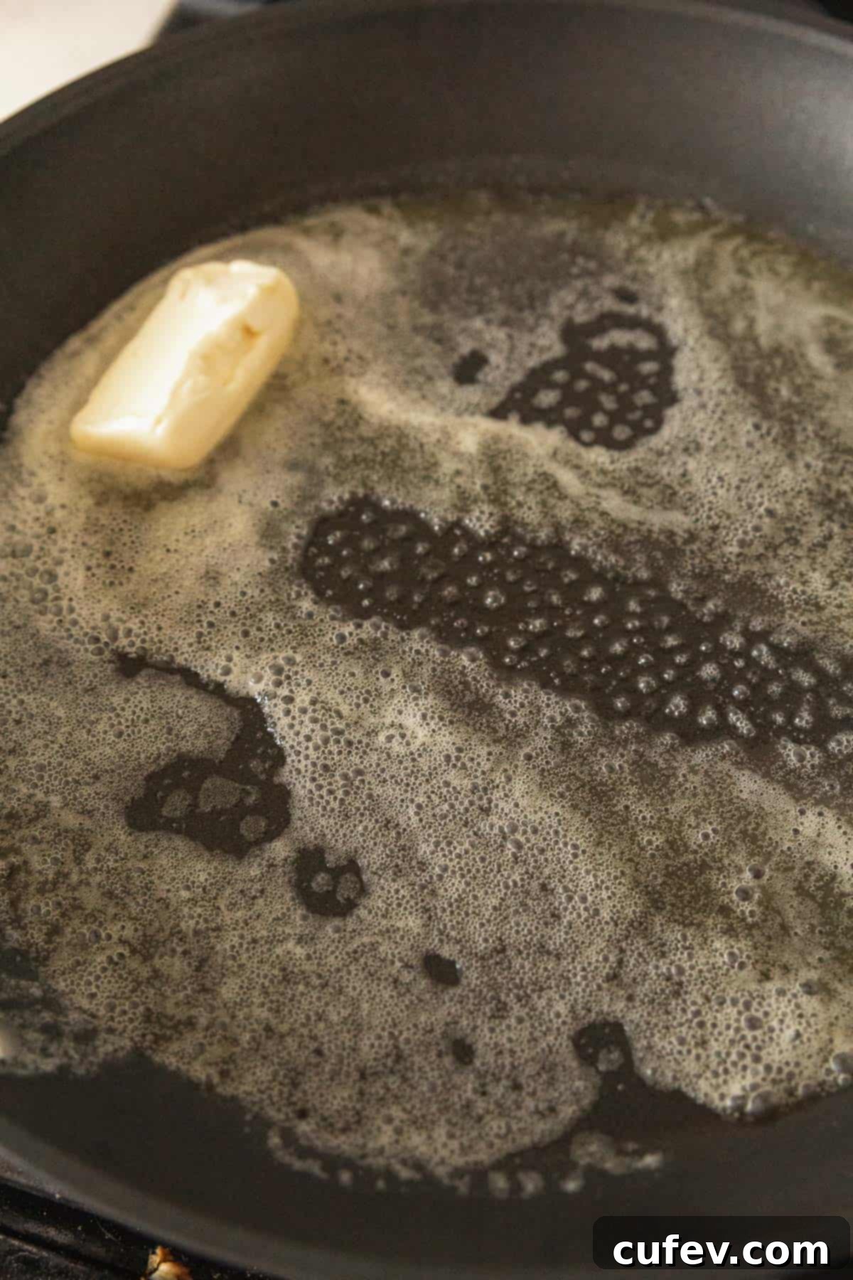 Cozy Vegan Bread Bake 7 Close-up shot of vegan butter melting and sizzling gently in a nonstick pan on a stovetop.