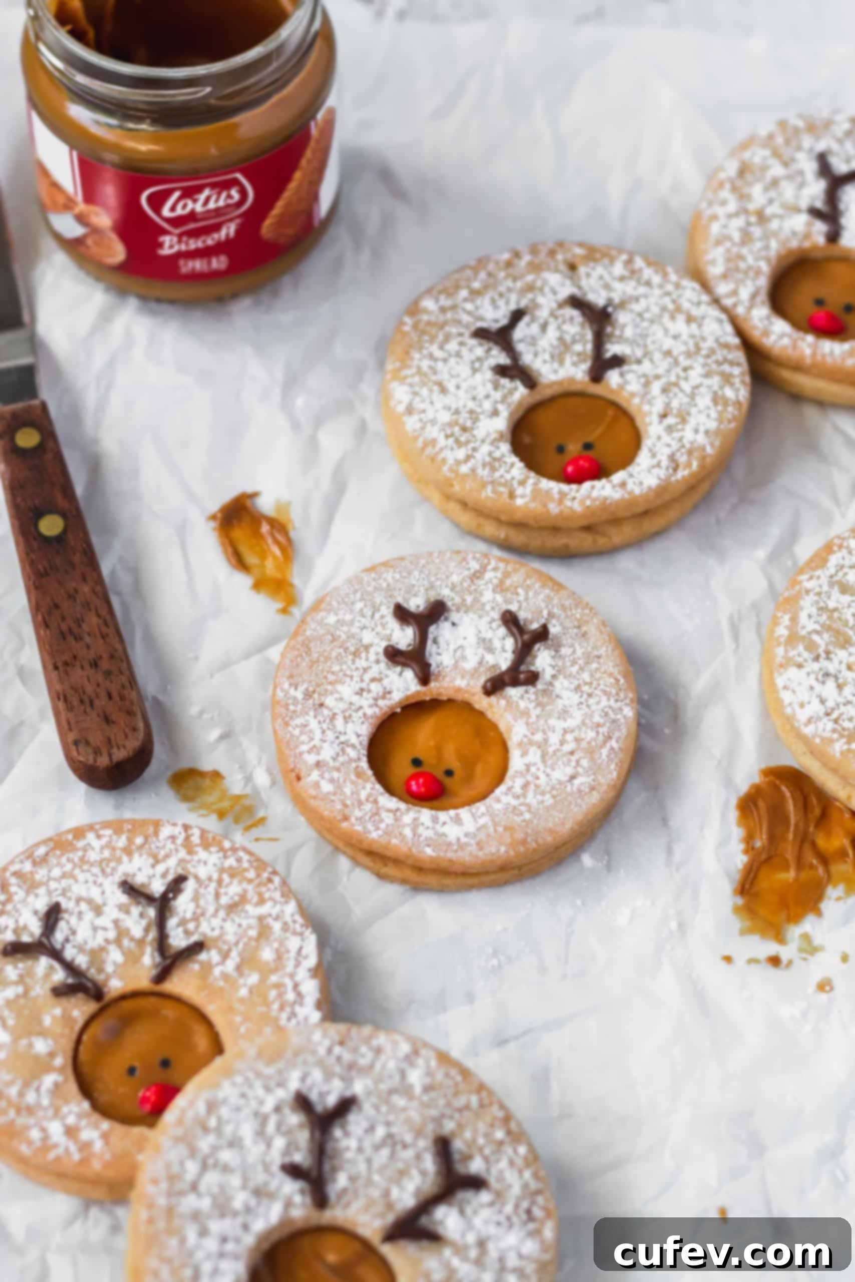 A collection of Rudolph reindeer cookies scattered on a piece of parchment paper, showcasing their whimsical design.