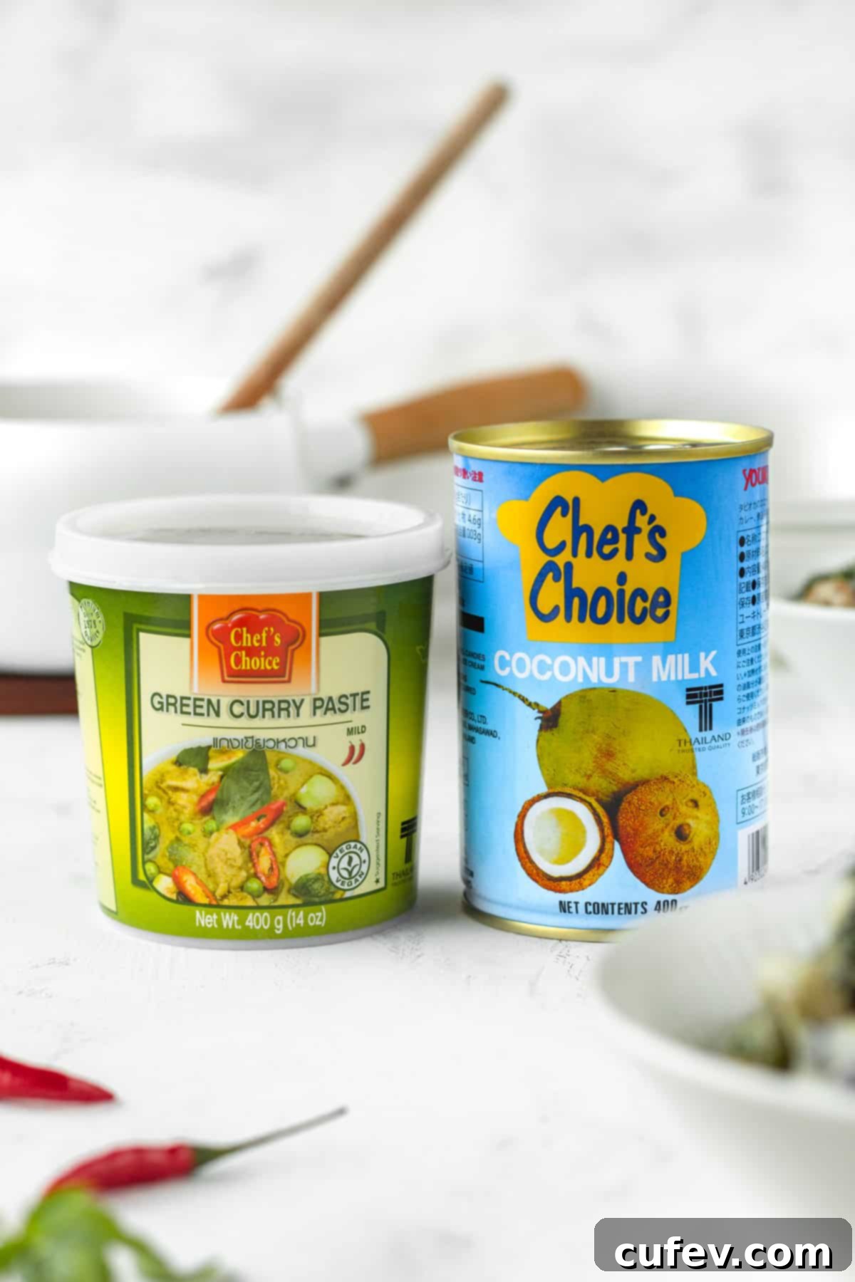 A can of coconut milk next to a container of green curry paste.