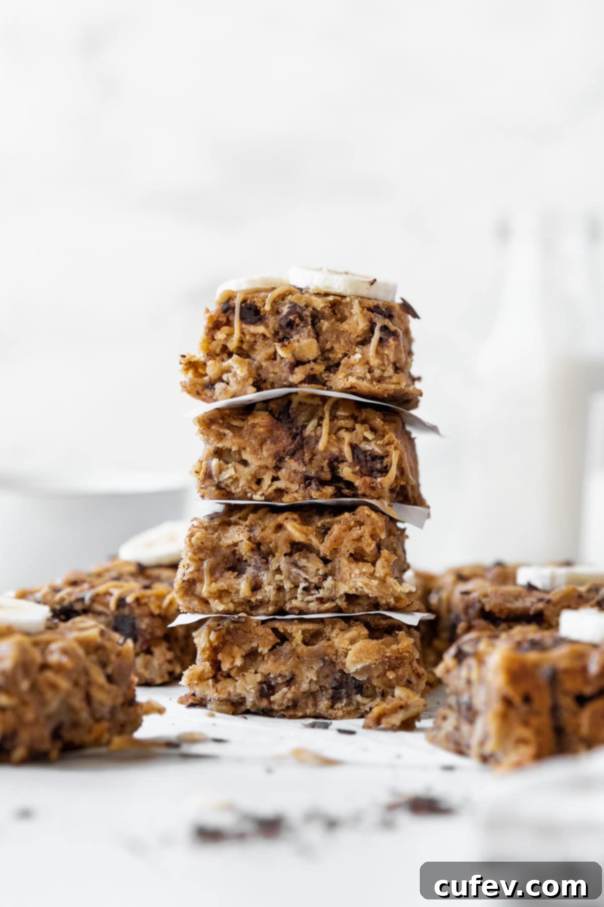 A side shot of a stack of peanut butter oatmeal breakfast bars on the counter with other bars in the background.