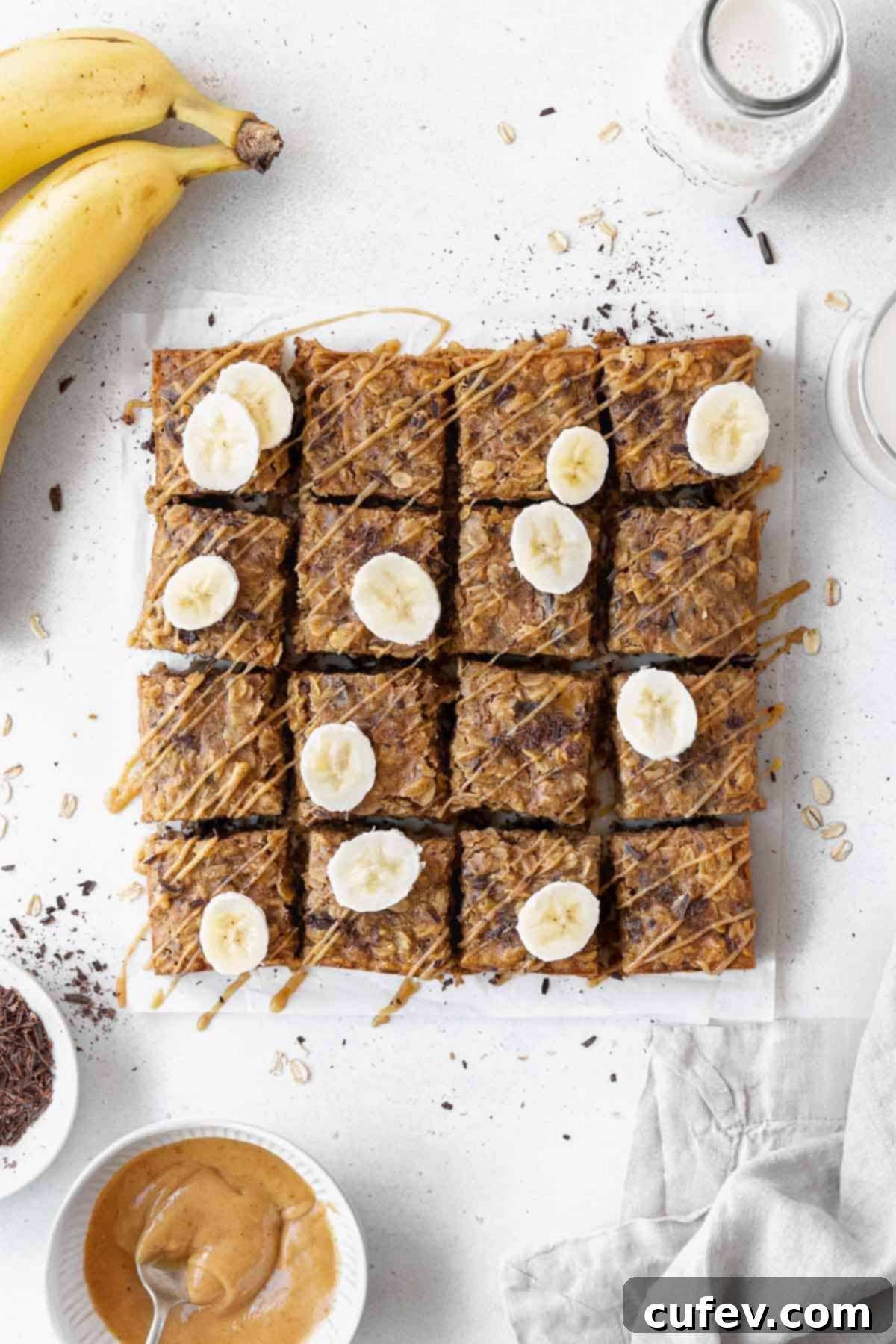 And overhead shot of pan of sliced peanut butter banana oatmeal bars on a piece of parchment paper.
