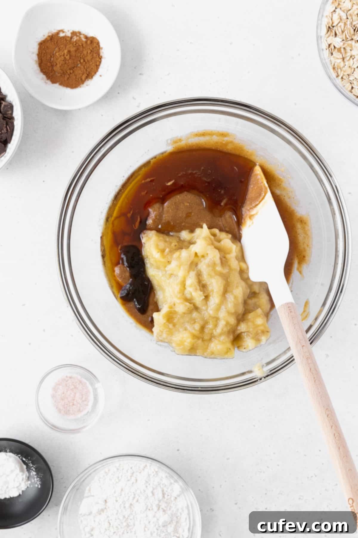 A mixing bowl with peanut butter, maple syrup, vanilla, and mashed bananas.