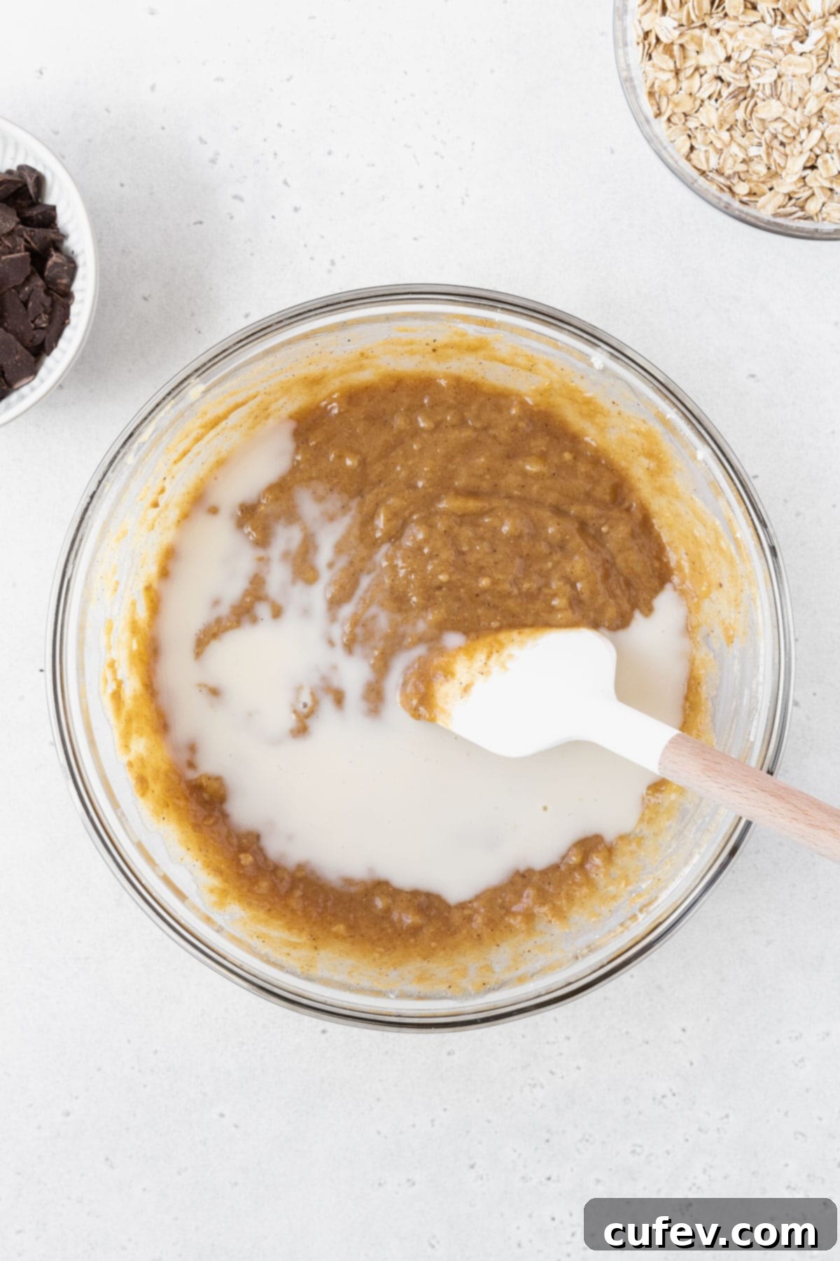 Stirring the milk into the bowl of peanut butter and banana bars batter.