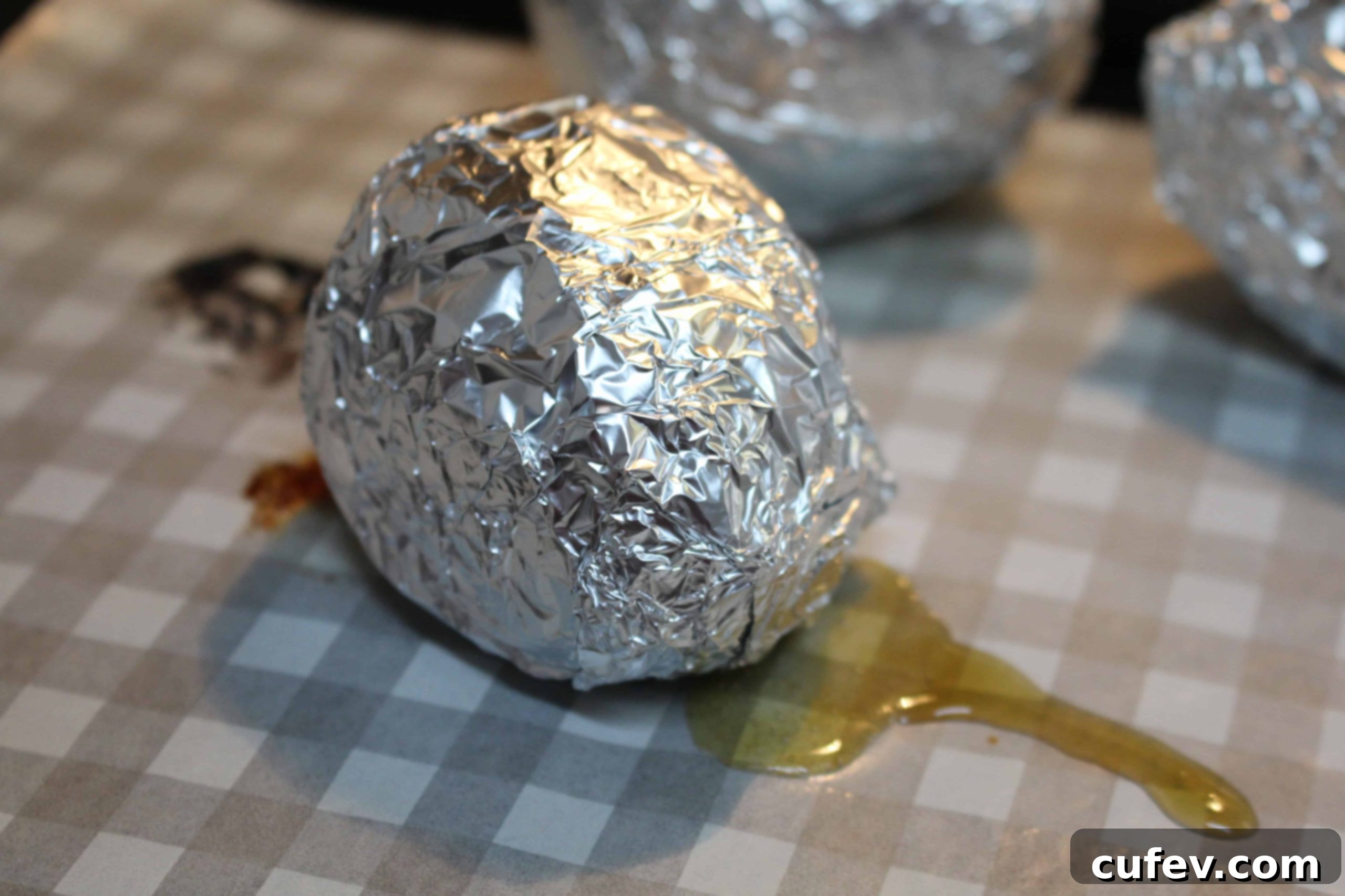 An Annoh-imo sweet potato, individually wrapped in aluminum foil on a baking sheet.