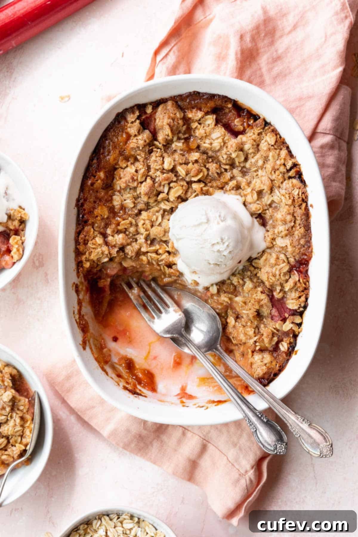 Rustic Rhubarb Crisp Gluten Free 4 Overhead shot of a casserole dish filled with the baked GF rhubarb crisp with a few portions taken out and a silver fork and spoon in the gap.