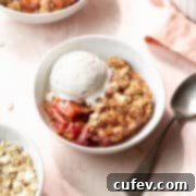 Rustic Rhubarb Crisp Gluten Free 5 Square hero shot of a bowl of gluten-free rhubarb crisp in a white bowl with a scoop of vanilla ice cream and a silver spoon.