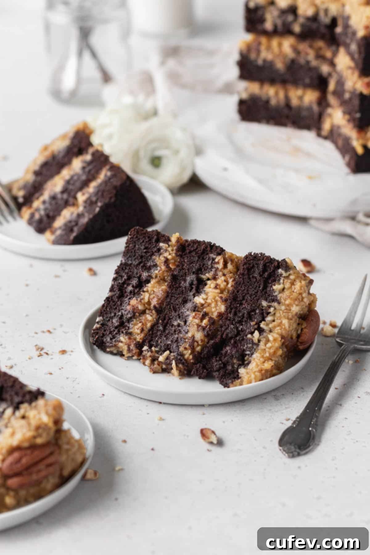 A slice of gluten-free German chocolate cake on a white dessert plate with a fork next to it.