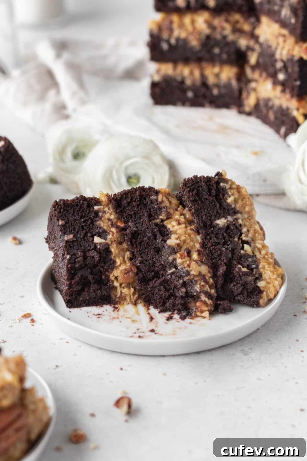 A slice of gluten-free dairy-free German chocolate cake on a white plate with a bite taken out.
