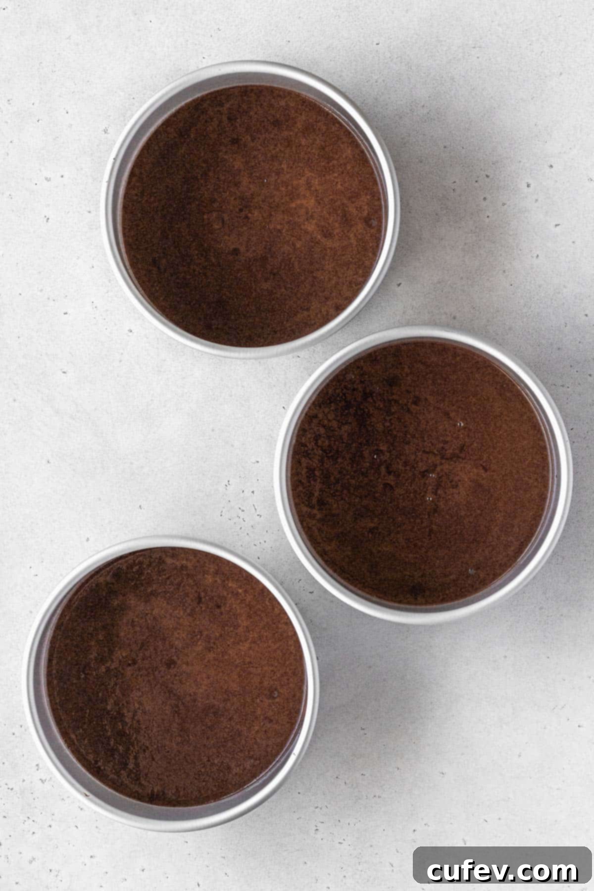 German chocolate cake batter in three 6 inch round cake pans.