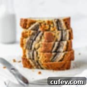 A stack of perfectly baked, super moist banana bread slices, showcasing a beautiful golden crust and tender interior against a crisp white background.