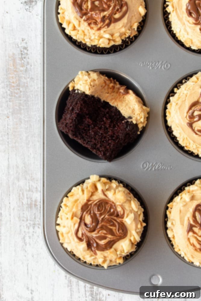A muffin pan filled with freshly baked chocolate peanut butter cupcakes, ready for frosting.