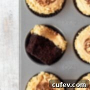 A delectable chocolate cupcake, generously topped with smooth peanut butter frosting, served in a muffin tin.
