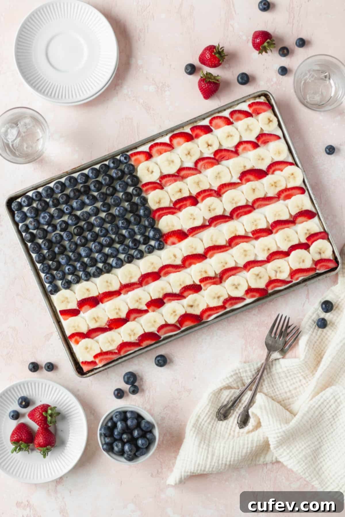 Overhead shot of an entire sheet pan of gluten-free and dairy-free American flag dessert pizza with vibrant blueberries, sliced bananas, and juicy strawberries, perfectly arranged for a patriotic celebration.