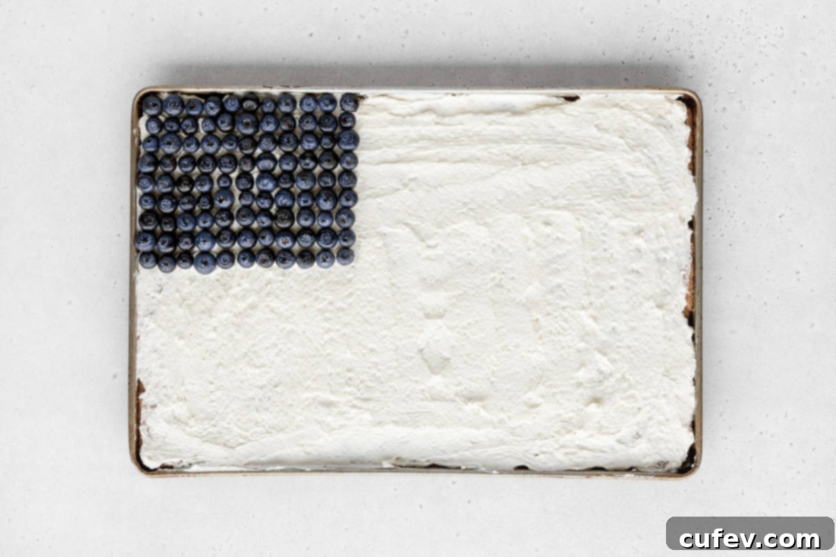 Vibrant blueberries carefully added to the upper left quadrant of the sheet pan, perfectly representing the stars portion of the American flag design on the fruit pizza.