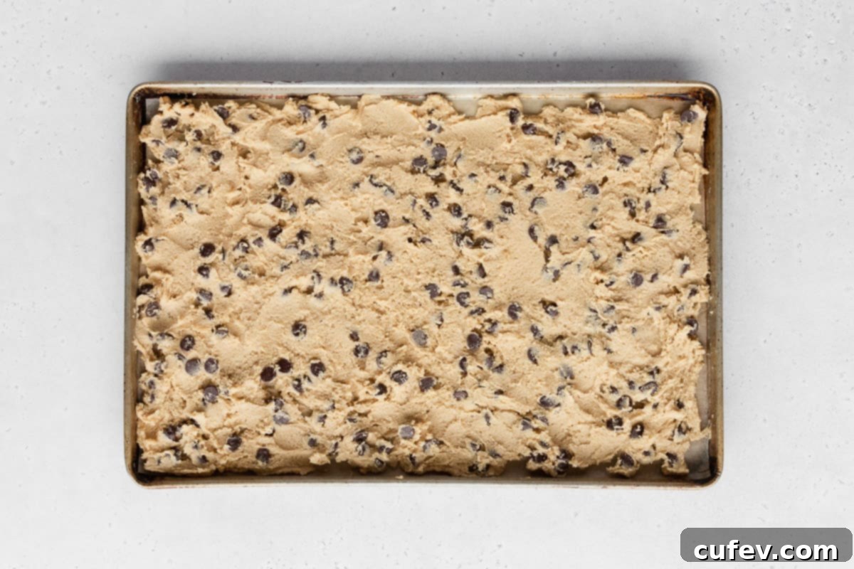 The entire batch of boxed cookie dough carefully spread out into an even layer across a sheet pan, ready for baking.
