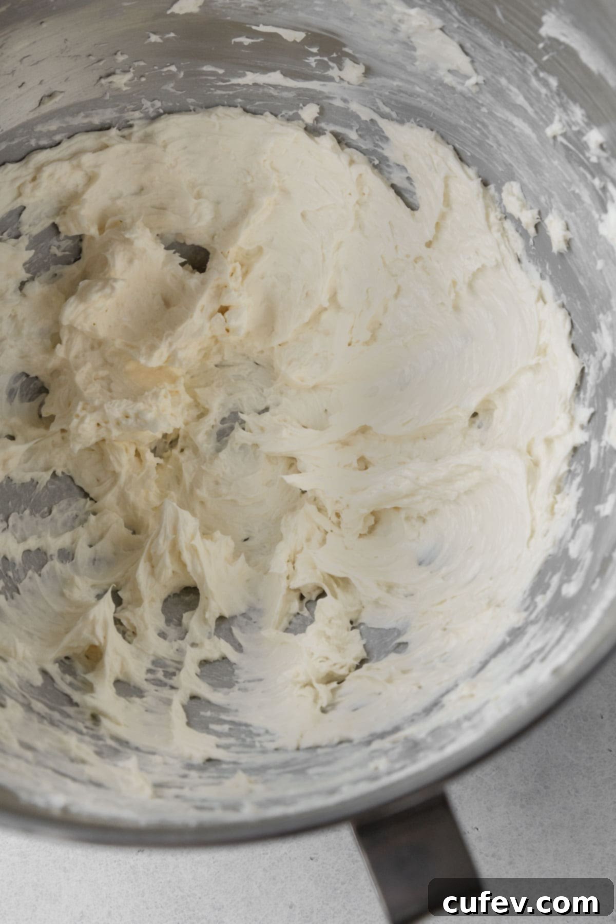 Softened vegan butter and vegan cream cheese creaming together in a mixing bowl, forming the delicious base for the frosting.