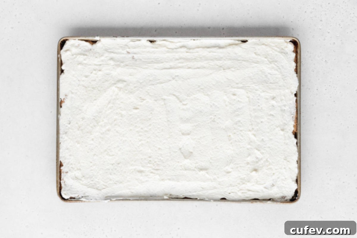 A pristine layer of smooth white cream cheese frosting expertly spread over the entirety of the sheet pan cookie, creating a perfect canvas for fruit.