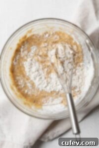 Dry ingredients being gently whisked into wet ingredients to form a muffin batter.