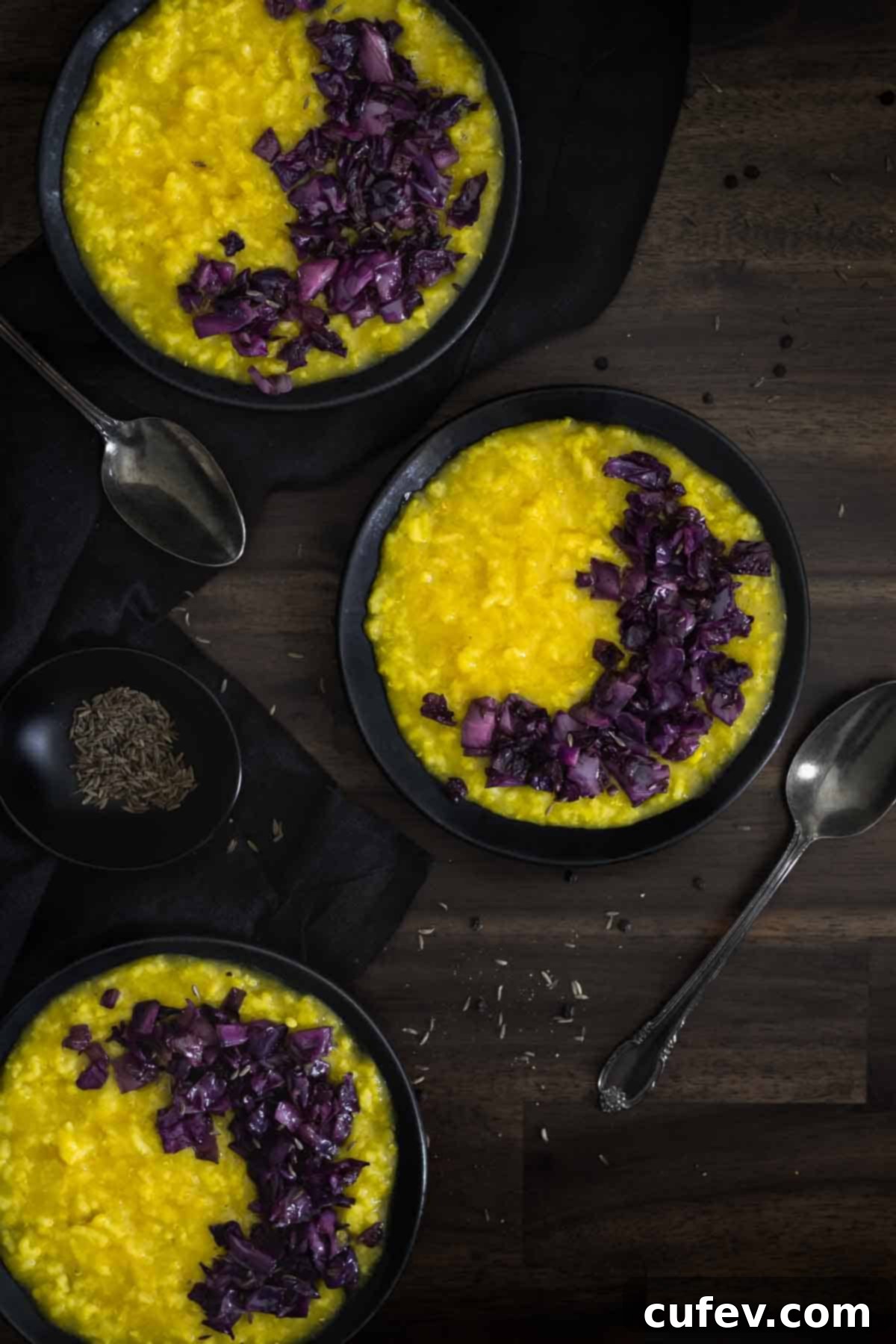 Three beautifully presented plates of Khichdi, topped with sautéed red cabbage and onions, ready to be served.