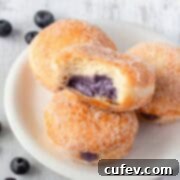 Blueberry donuts on a plate filled with blueberry cream cheese filling.