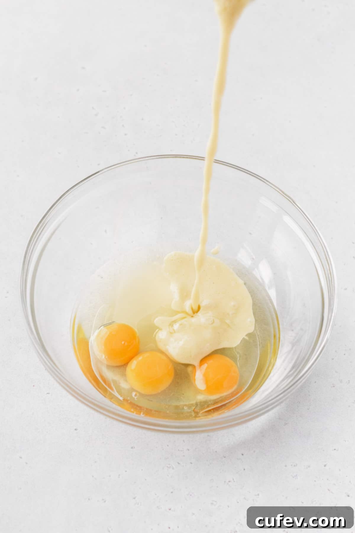 Golden Gluten-Free Cornbread Delight 7 Corn and milk mixture being poured into a bowl with eggs and oil, ready to be combined with other wet ingredients.