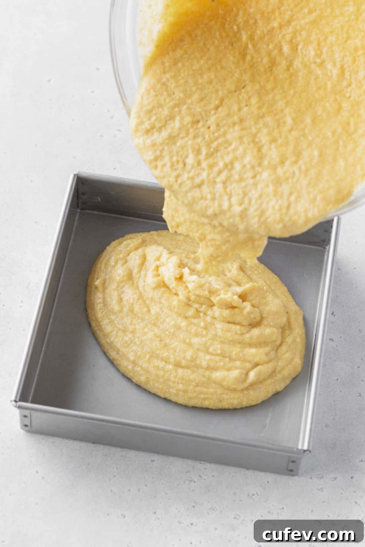 Golden Gluten-Free Cornbread Delight 10 Pouring gluten-free cornbread batter into a prepared 8x8 baking tin.