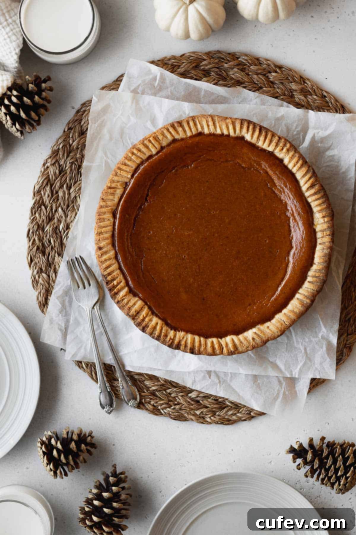 An inviting overhead shot of a freshly baked non-dairy pumpkin pie resting on crinkled parchment paper, its surface smooth and ready for cooling.