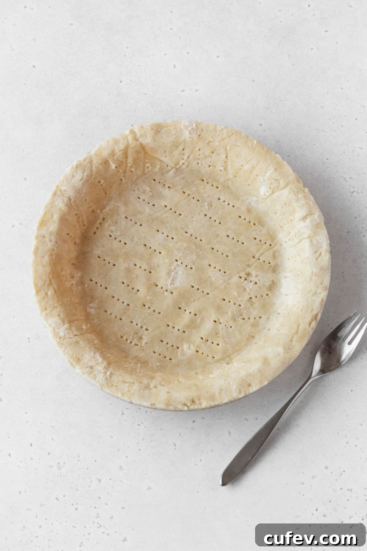 A meticulously pressed pie dough fitted into a glass pie plate, ready for the next stage of baking, illustrating proper crust preparation.