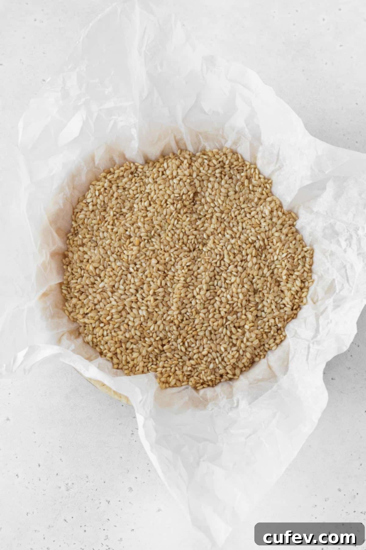 A crinkled piece of parchment paper carefully placed on top of pie dough and filled with dry brown rice, demonstrating the blind baking technique to prevent bubbling.
