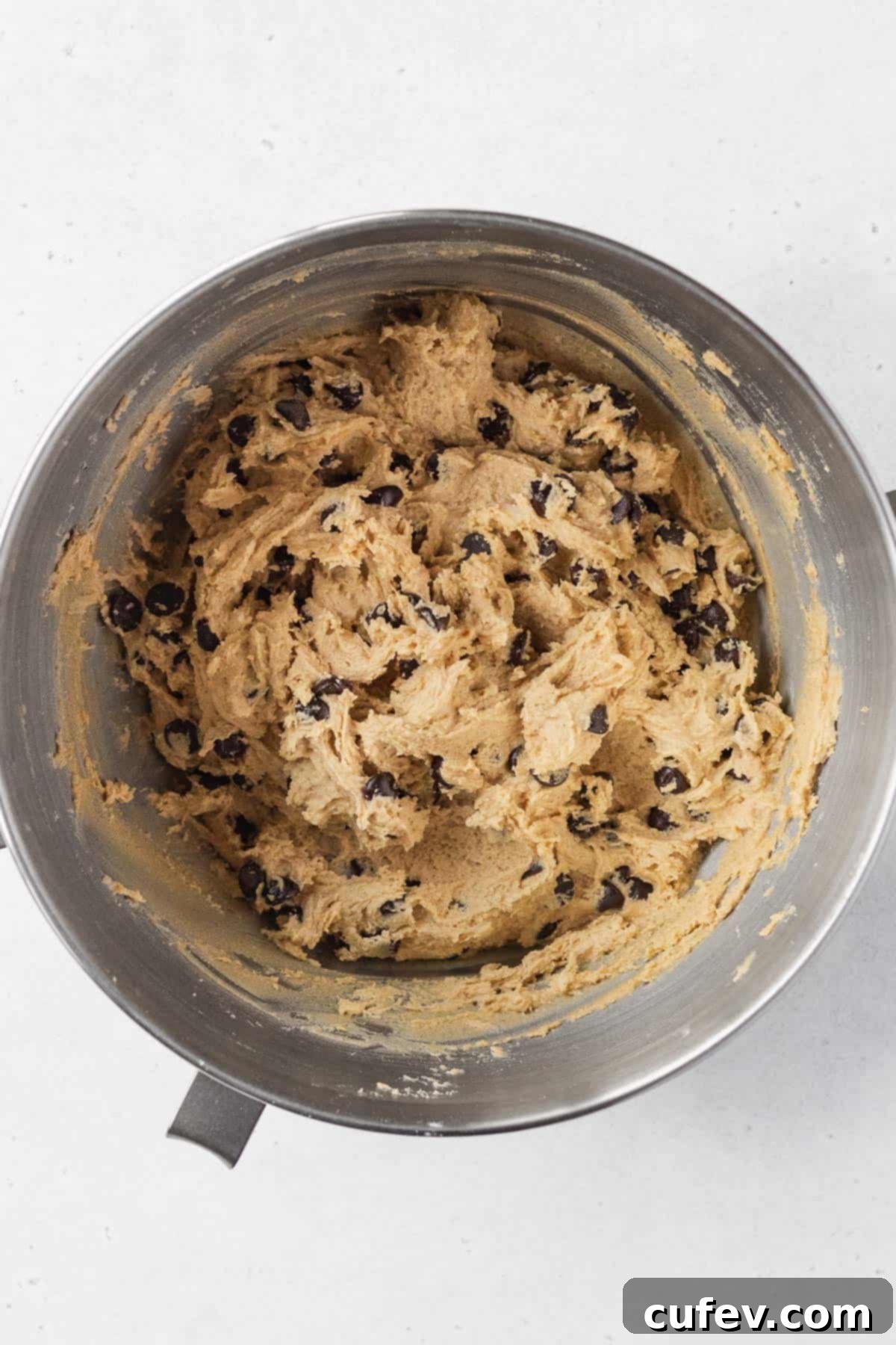 Gluten-free dairy-free chocolate chip cookie dough after chocolate chips have been folded in, showing a thick and cohesive texture in a bowl.