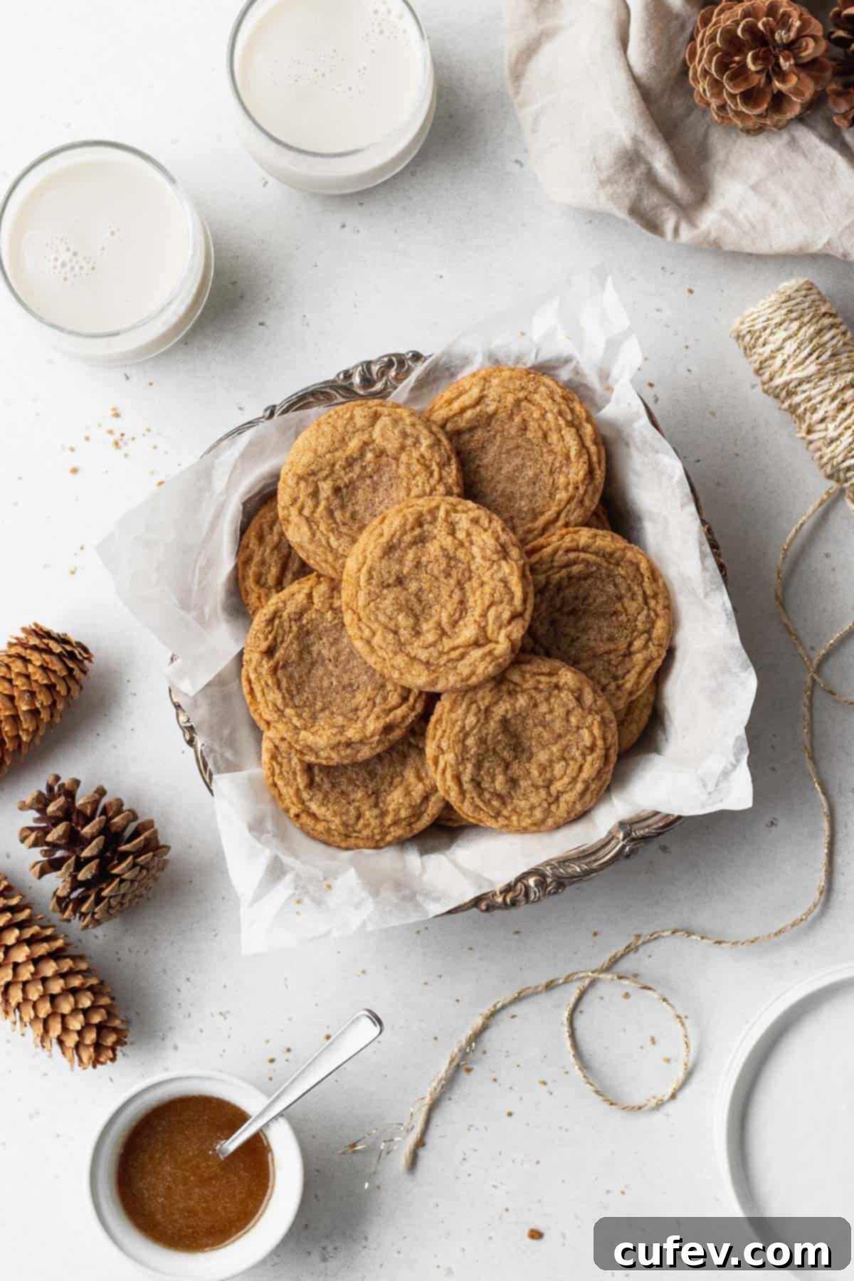 Perfectly Chewy Gluten-Free Ginger Cookies 2 A platter of gluten free ginger snaps surrounded by glasses of milk, pine cones, string, and a dish of maple glaze icing.