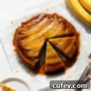 A banana upside down cake on parchment paper with two slices cut out, showing its golden topping.