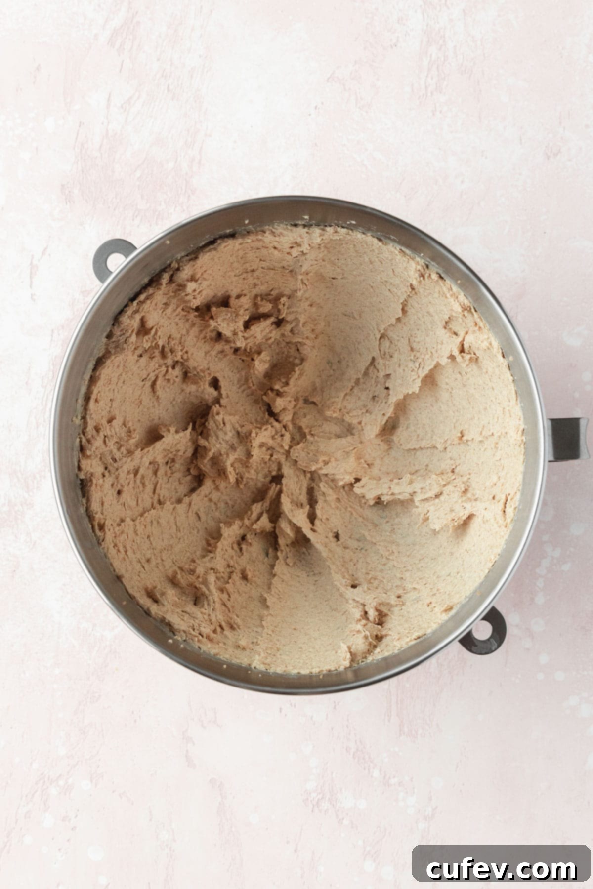 Creamed butter, brown sugar, and granulated sugar in a silver mixing bowl, showcasing a light and fluffy texture after beating.