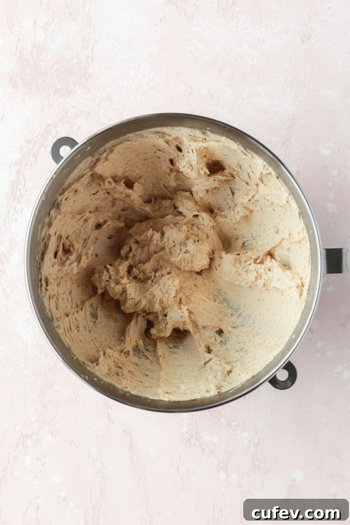 Wet ingredients including creamed butter and sugars, egg, honey, and vanilla extract, fully combined and smooth in a silver mixing bowl, ready for dry ingredients.