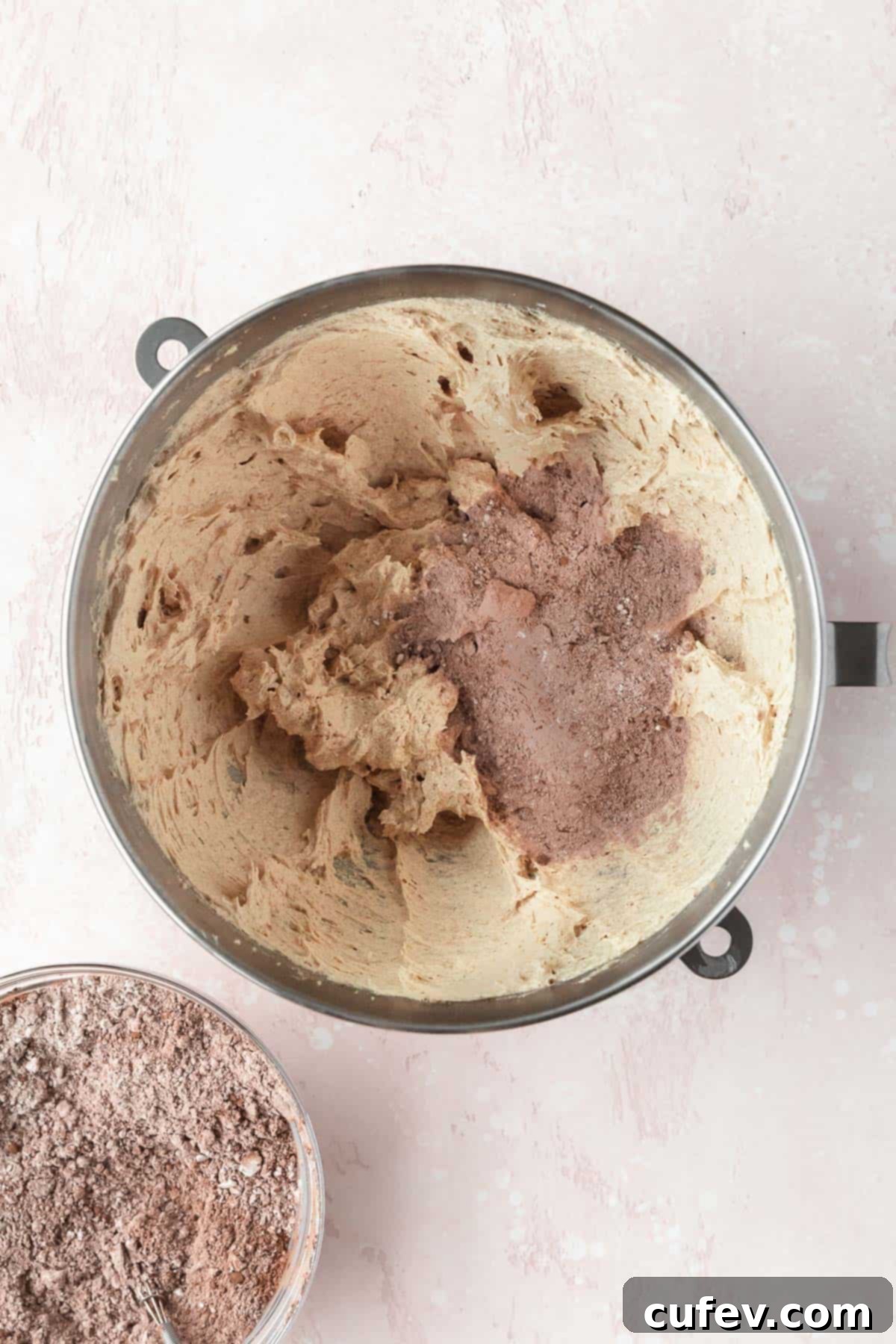 Dry ingredients being gradually added to the wet, creamed butter mixture in a mixing bowl, showing the dough forming and being gently combined.
