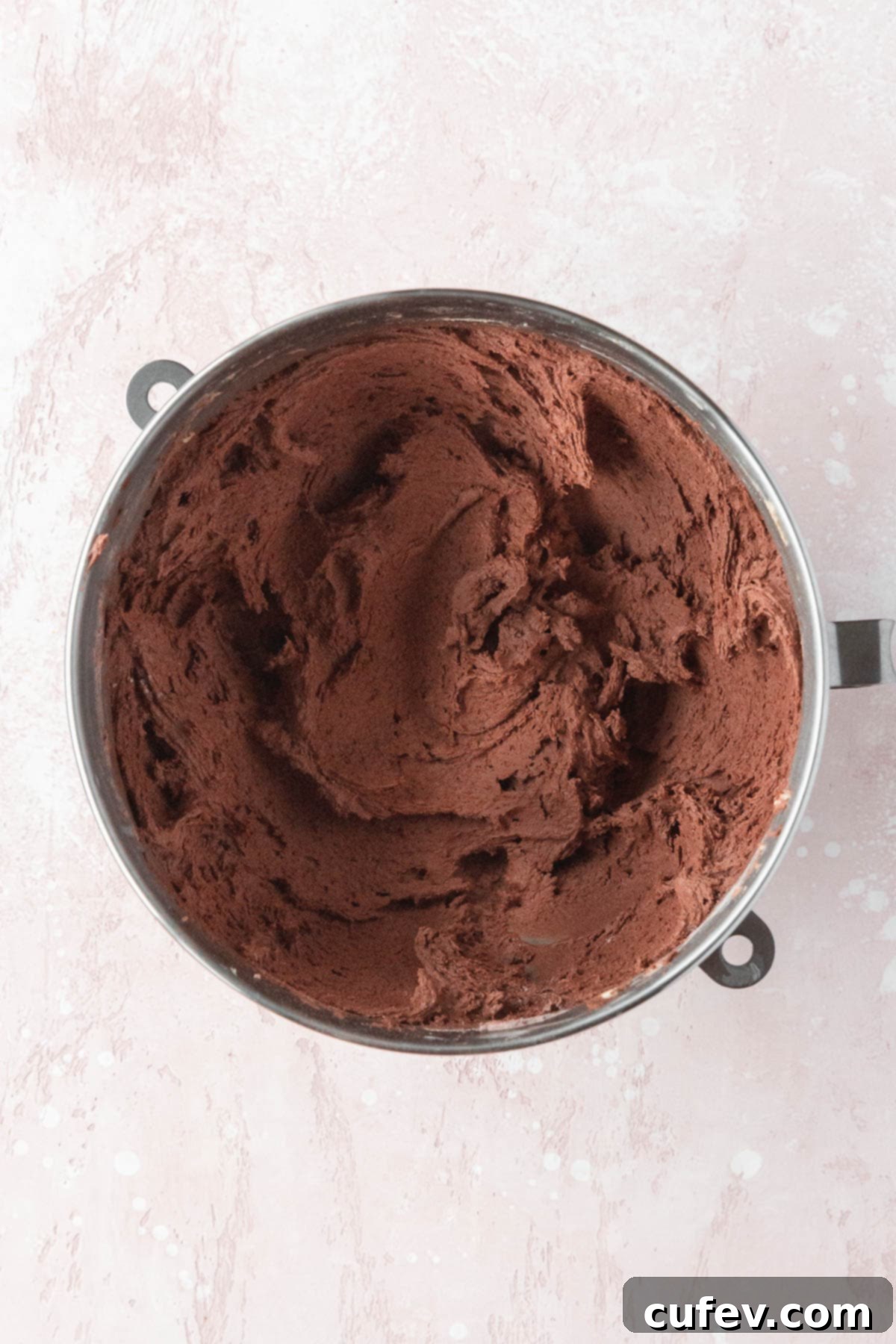 Rich double chocolate cookie dough resting in a mixing bowl, showcasing its dark, dense consistency after all ingredients have been combined.