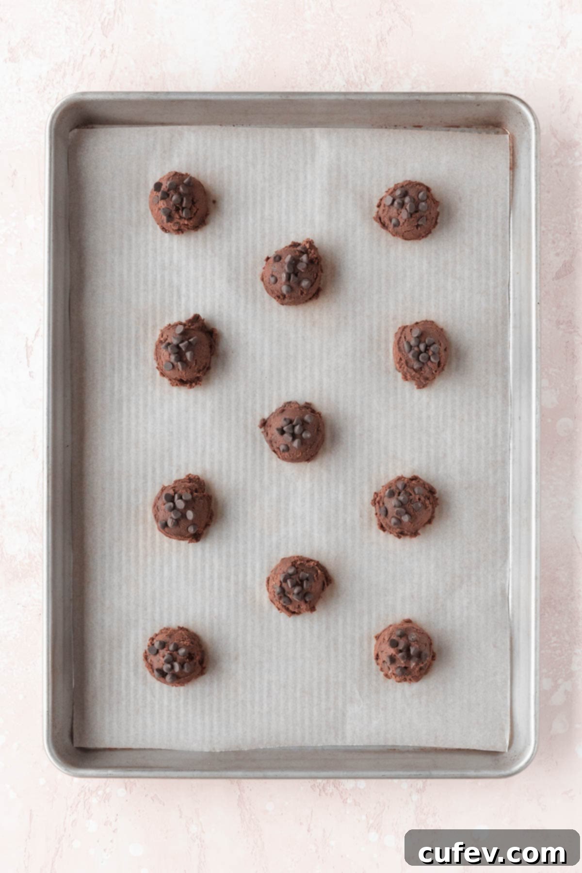Scooped double chocolate cookie dough balls arranged on a baking sheet lined with parchment paper, spaced out for even baking.