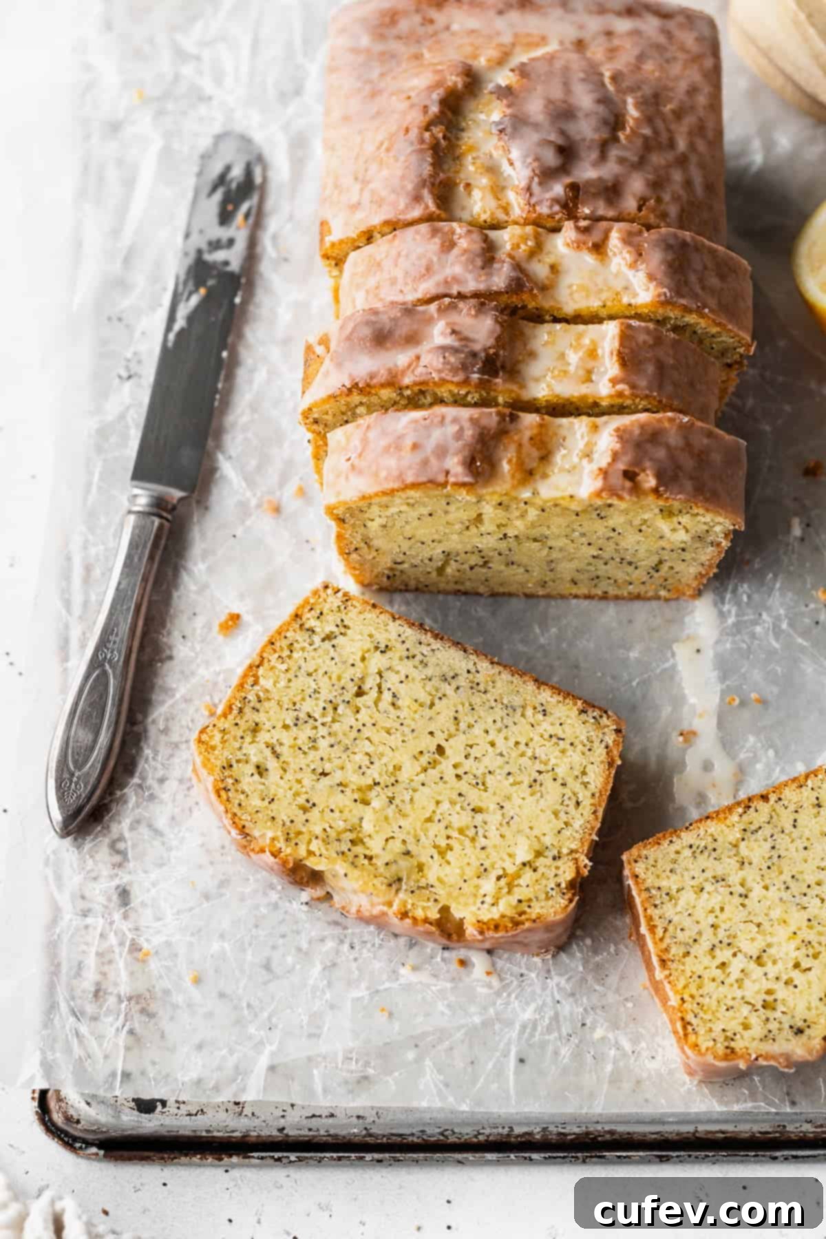 Overhead shot of a sliced lemon poppysead loaf with two slices laying in front of it.